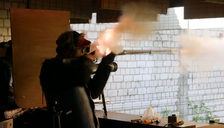 Ein Vorderladerschütze im sportlichen Wettkampf. Man sieht das Pulverfeuer am Hahn und an der Mündung des Laufes.