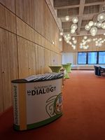 Blick in einen Raum mit einer Theke, auf der Logo des Projekts "Schützen im Dialog" zu sehen ist.