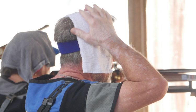 ein Sportschütze, der versucht, sich mit einem feuchten Tuch auf dem Kopf abzukühlen. (Foto: Lutz Berger)