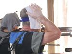 ein Sportschütze, der versucht, sich mit einem feuchten Tuch auf dem Kopf abzukühlen. (Foto: Lutz Berger)